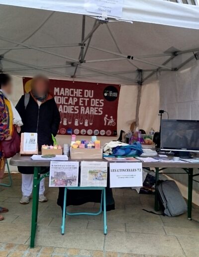 Journée de la Solidarité 2025 : bénévoles au stand des Étincelles 72 sous la banderole de la Marche du handicap