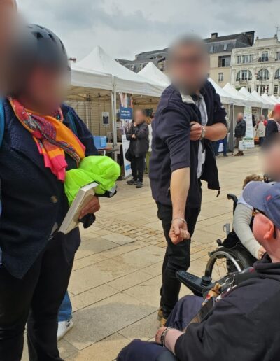 Journée de la Solidarité 2025 : échanges entre participants sur la place, dont une personne en fauteuil roulant
