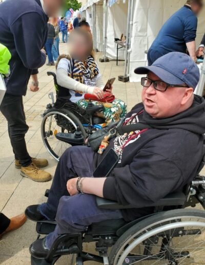 Journée de la Solidarité 2025 : participant en fauteuil roulant souriant près des stands