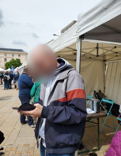 Journée de la Solidarité 2025 : visiteur consultant son téléphone près des stands