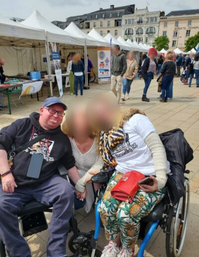 Journée de la Solidarité 2025 : trois membres de l'association posent ensemble, dont deux en fauteuil roulant