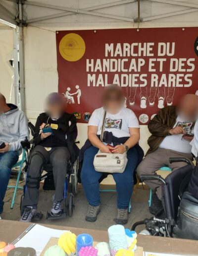Journée de la Solidarité 2025 : bénévoles installés sous la tente des Étincelles 72, banderole de la Marche du handicap