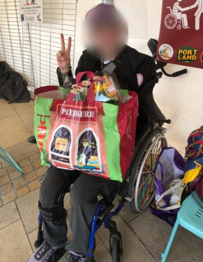 Journée de la Solidarité 2025 : participante en fauteuil roulant avec un sac de pâtisseries